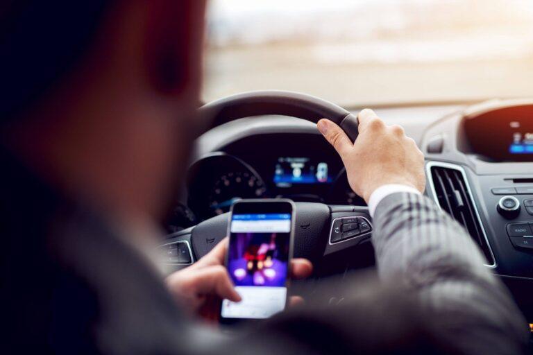 Man looking at mobile phone while driving a car