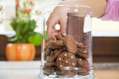 Children's hand in the cookie jar grabbing a cookie